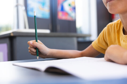 Biracial boy focused on writing in a classroom at school