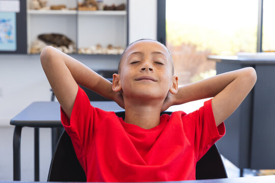 Biracial boy relaxes in a classroom at school