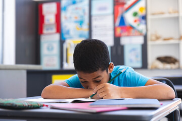 Biracial boy focused on schoolwork in the classroom at school