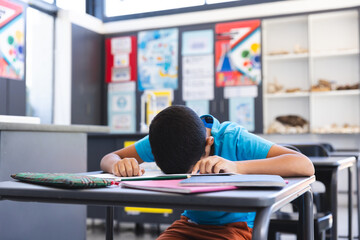 Biracial boy studying intently in a classroom at school