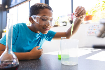Biracial boy engaged in a science experiment at school in the classroom