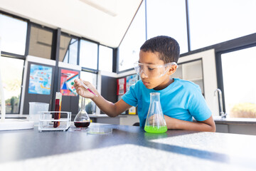 Biracial boy engaged in a science experiment at school in a classroom with copy space