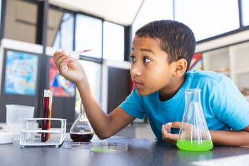 Biracial boy engaged in a science experiment at school in the classroom