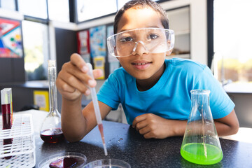 Biracial boy engages in a science experiment at school in the classroom