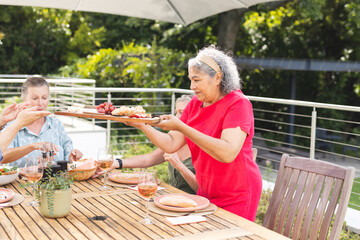Diverse senior female friends sharing meal outdoors - Powered by Adobe