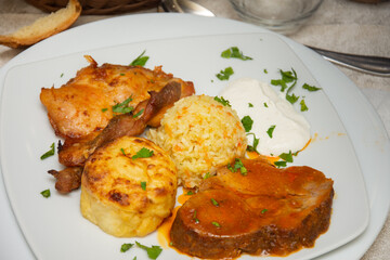 A plate with chicken meat, fried potatoes and rice