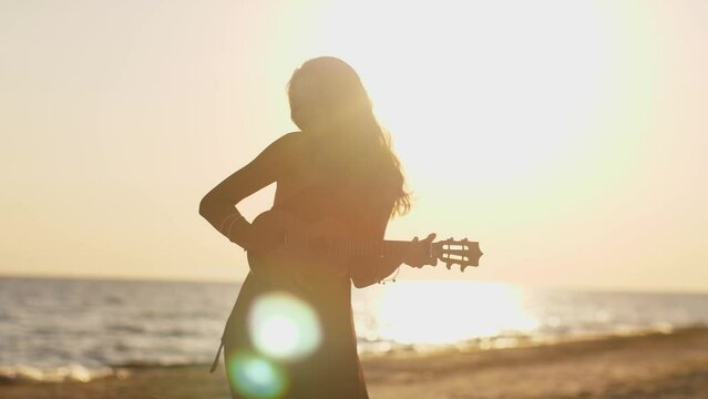 Woman Playing Ukulele on Beach at Sunset. Summer beach vibes
