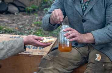 two men sitting outdoors Spreading honey on a biscuit