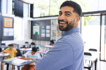 In school, a young Asian male teacher with black hair, smiling, with copy space, in the classroom