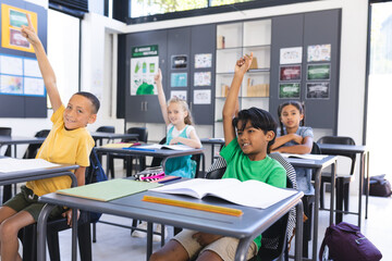 Eager children raise their hands in a bright school classroom