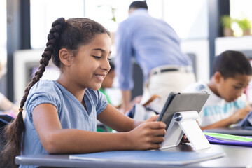Biracial girl with braids uses tablet in class, embracing education concept