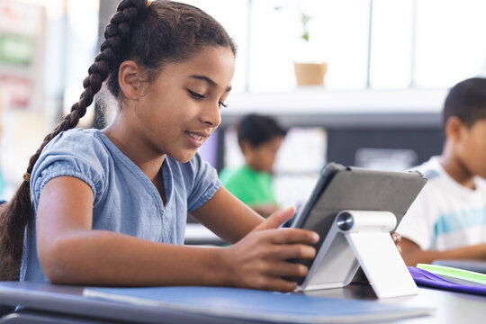 In school, young biracial female student using a tablet in the classroom - Powered by Adobe