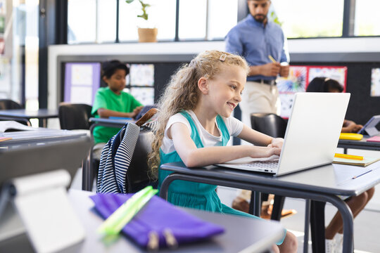 In school, diverse group of young students focusing on laptops in the classroom