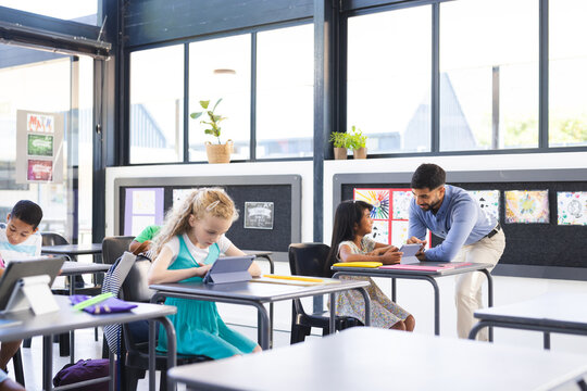 In school, diverse group of students learning with their Asian male teacher in the classroom
