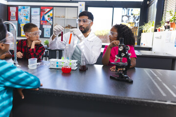 Kids observe Asian male teacher doing science test