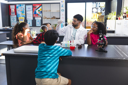 In school, Asian male teacher showing chemistry experiment to young students