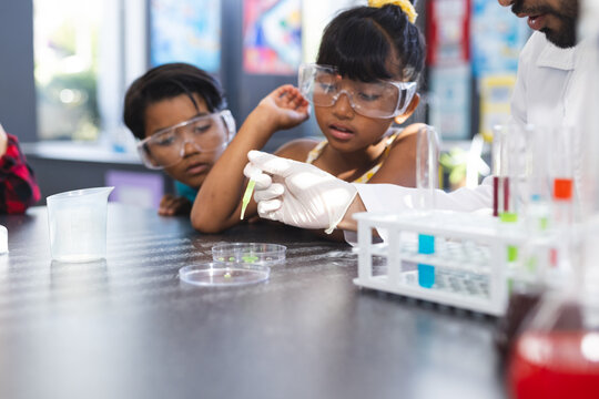 Biracial girl and boy watch a science experiment with interest in school