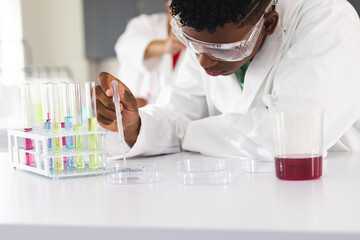 Teenage biracial boy conducts an experiment in a high school lab