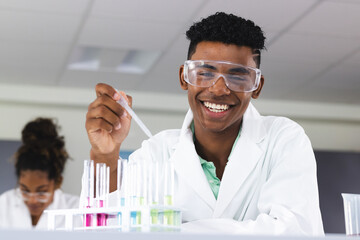 Teenage biracial boy conducts an experiment in a high school lab