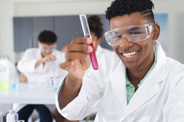 Teenage biracial boy examines a test tube in a high school lab