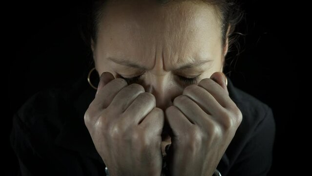 Female with issues with bound hands. A view of unhappy female with metal chain on her hands sitting in loneliness in the dark.