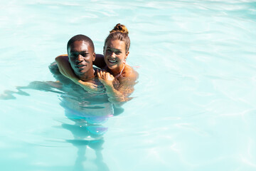 A diverse young couple smiling outside in blue background