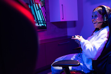 A biracial young girl wearing headphones, gaming at home