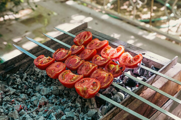 halved tomatoes on charcoal fire being barbecued 