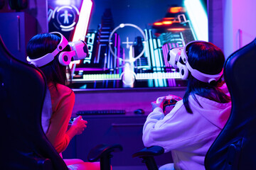 Biracial young sisters, at home, wearing gaming headsets, playing video games