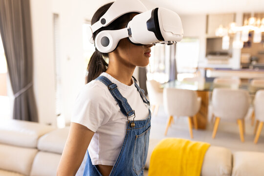 A biracial young girl wearing VR headset at home, exploring a digital world