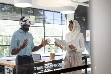 In modern business office, African American man in VR headset, part of diverse team