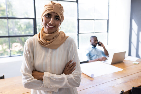 In modern business office, diverse team with young woman in beige hijab standing