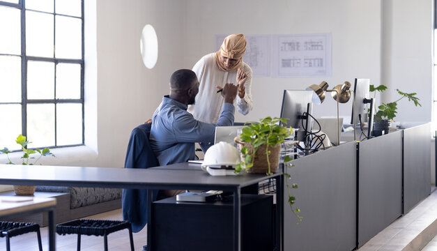Diverse team in modern business office celebrating success with fist bump