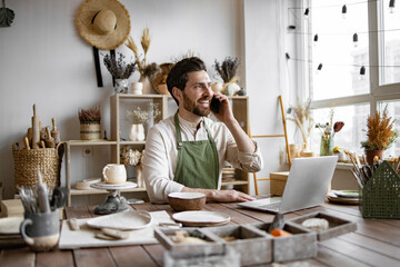 Successful businessman owner of shop made of clay talking to customer. Caucasian male potter...