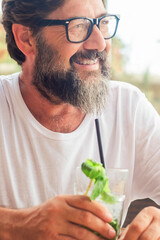 Portrait of serene happy adult man drinking mojito cocktail at the cafe bar in summer holiday vacation outdoor leisure activity. Tourist enjoying relax. One mature male smiling sitting at the table