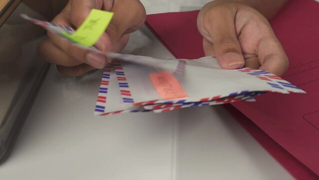 person sorting envelopes on white table