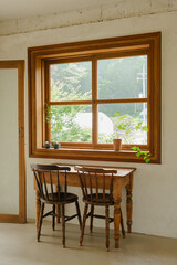 Rustic wooden table and chairs by large window