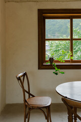 Wooden chair by a window with outdoor greenery view