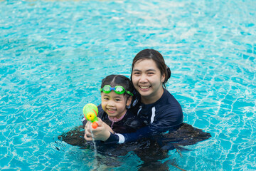 A woman and a child are in a pool, the woman is holding a toy gun and the child is holding a toy gun