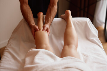 Woman client suffering from cramps enjoying legs sports massage therapy