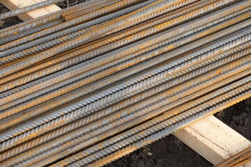 A close-up shot of a stack of rusty rebar on a construction site