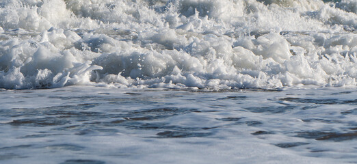 Beautiful blue sea and large calm waves and foam. Wave splashing over pebbles at sea. Rolling ocean...