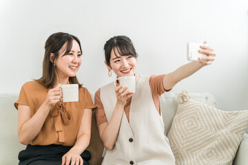 カフェで友達と自撮り・セルフィーをするアジア人女性
