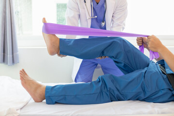female doctor using elastic bands help patient regain muscle movement after recuperating from...