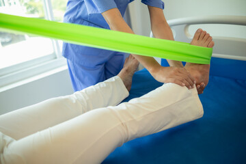 female doctor using elastic bands help patient regain muscle movement after recuperating from...