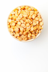 Uncooked, yellow peas in bowl on white background. Top view. Space for a text