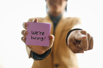 Businessman Pointing To You And Showing We're Hiring On Sticky Note.
