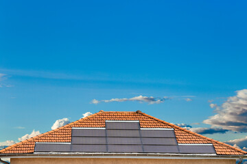 Solar panels on houseroof in front of blue sky with sun Sustainable Energy Solution: Solar Panels on House Rooftop Generating Clean Power in Urban Environment. Solar panels on the roof of a House.
