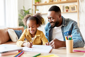 Fototapeta premium Smiling father helping his daughter with her homework at home, enjoying quality time together.