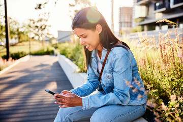 Woman using phone siting outdoors in city